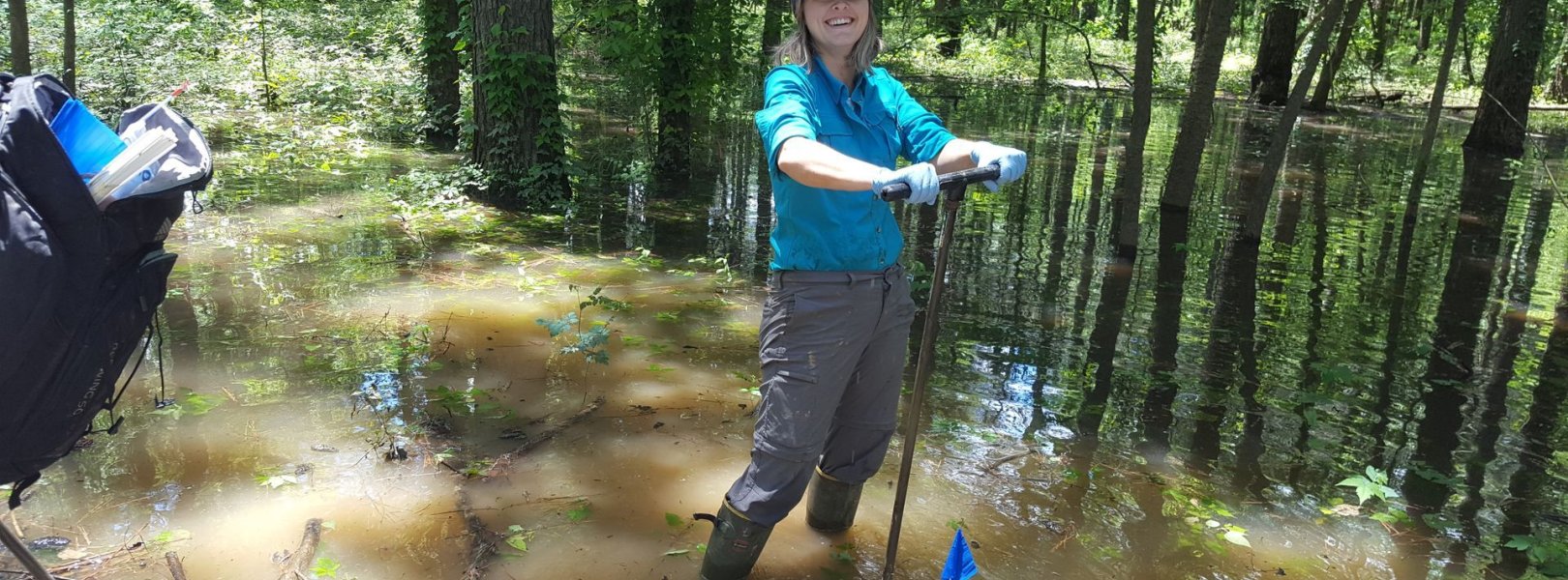 Field technician soil sampling in a forest floodplain at the DELA field site