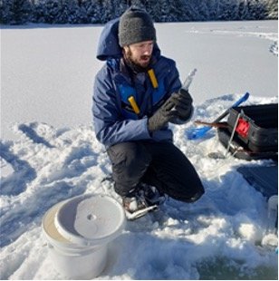 NEON field ecologist samples surface water for microbes during winter at D05 CRAM (Photo by Hannah Beeler)