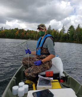 Domain 05 field ecologist prepares to collect aquatic plants at the CRAM lake field site using a rake