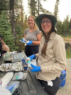 Laura Meredith and Meara Clark working from their tailgate lab bench to cut fresh soil core samples from the Delta Junction NEON