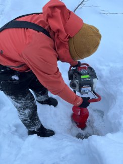 Eli Gomez boring a hole through the ice on Caribou Creek for water samples AOS sampling in January. 