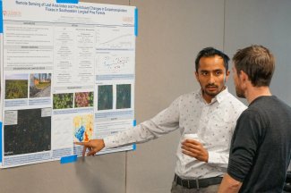 Siddhartha Regmi points at a poster and speaks to other workshop attendees.