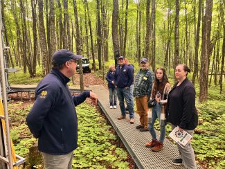 Visitors listening to the University of Notre Dame Environmental Research Director on a walkway at the UNDE field site tower.