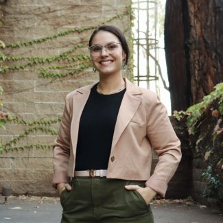 Gabriela Shirkey smiling with hands in pockets in a courtyard.