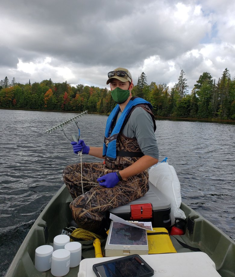 Domain 05 field ecologist prepares to collect aquatic plants at the CRAM lake field site using a rake